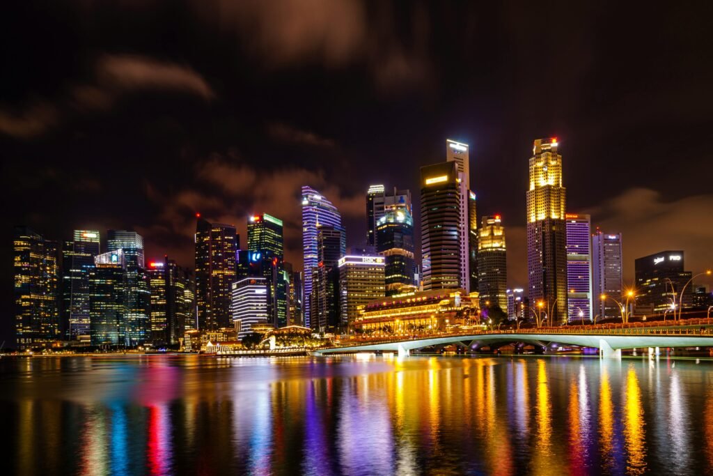 Vibrant night view of Singapore skyline with city lights reflecting on water.