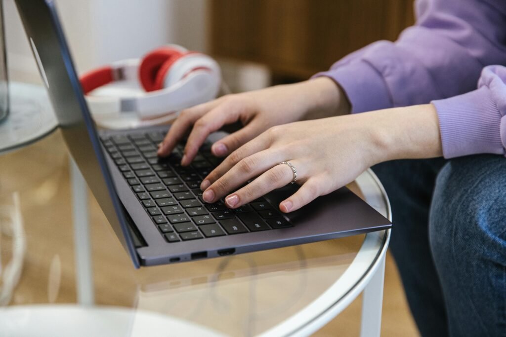 Close-up view of hands typing on a laptop indoors, showcasing technology and productivity.